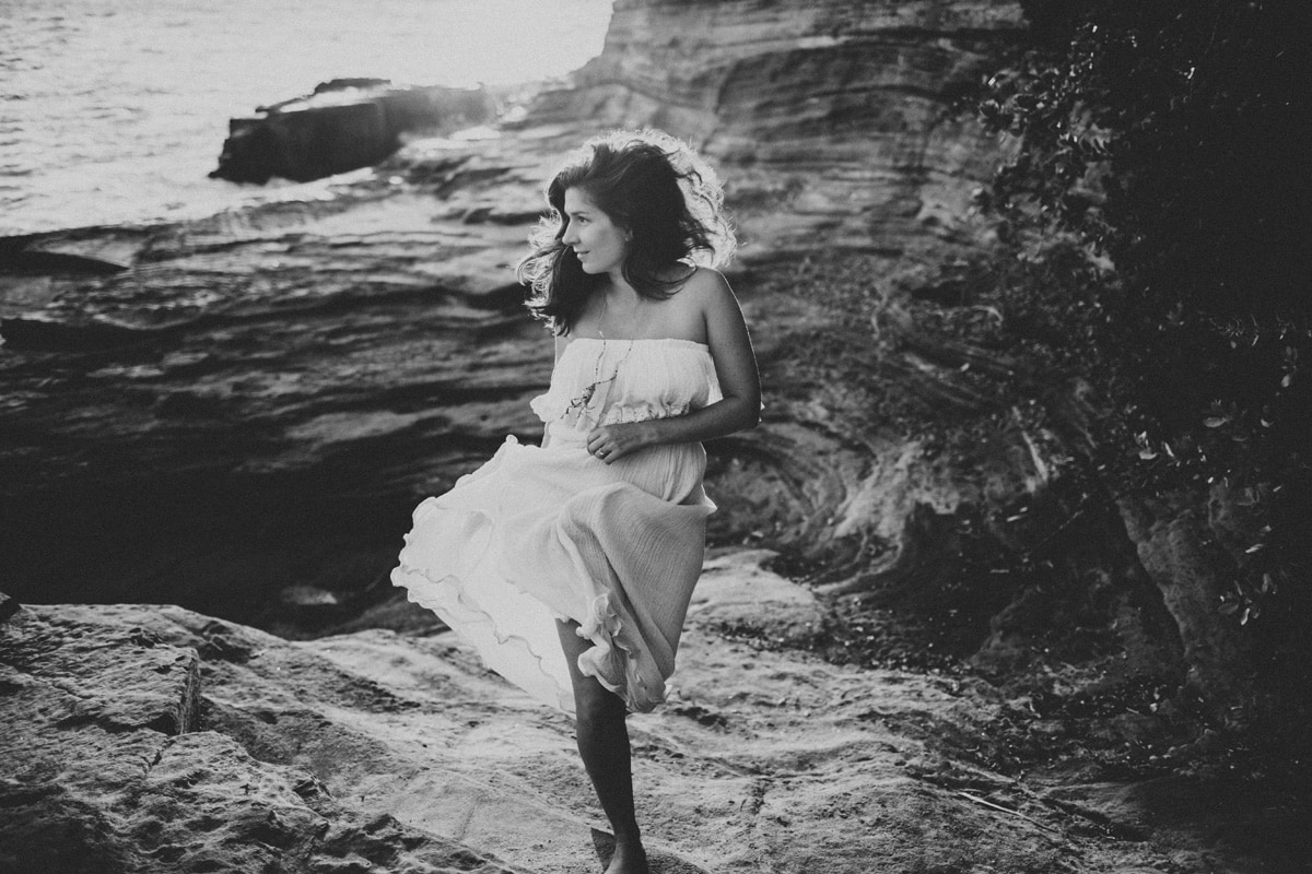 Family Photographer, woman in white dress runs on across rocks in desert canyons