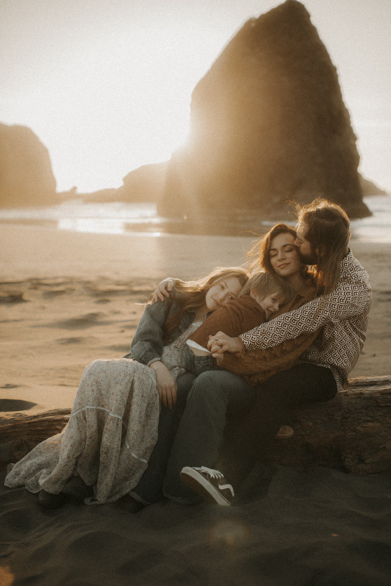 Family photography, family of four sitting on beach cuddled up into dad